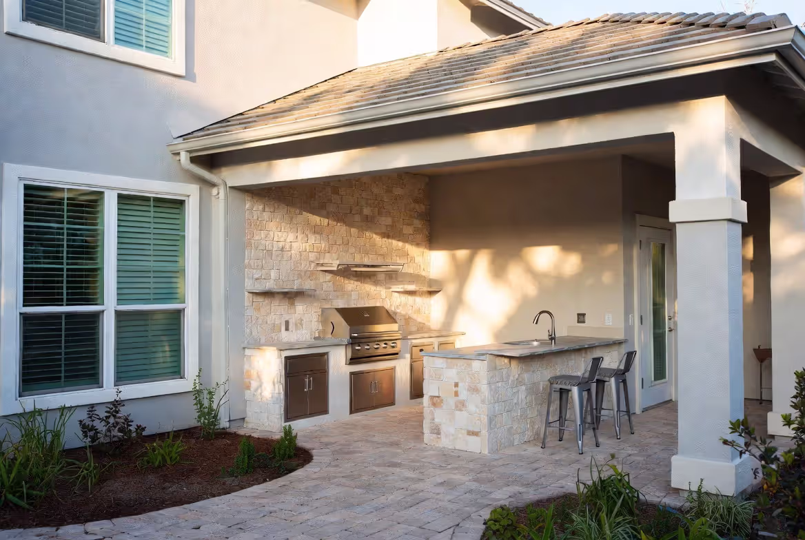 outdoor kitchen installed against exterior house wall under lanai